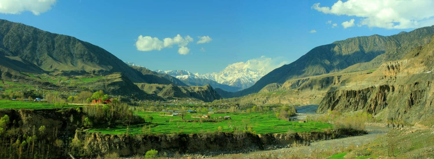 Chitral's cultivated valley floor beneath a snow-capped Hindu Kush peak