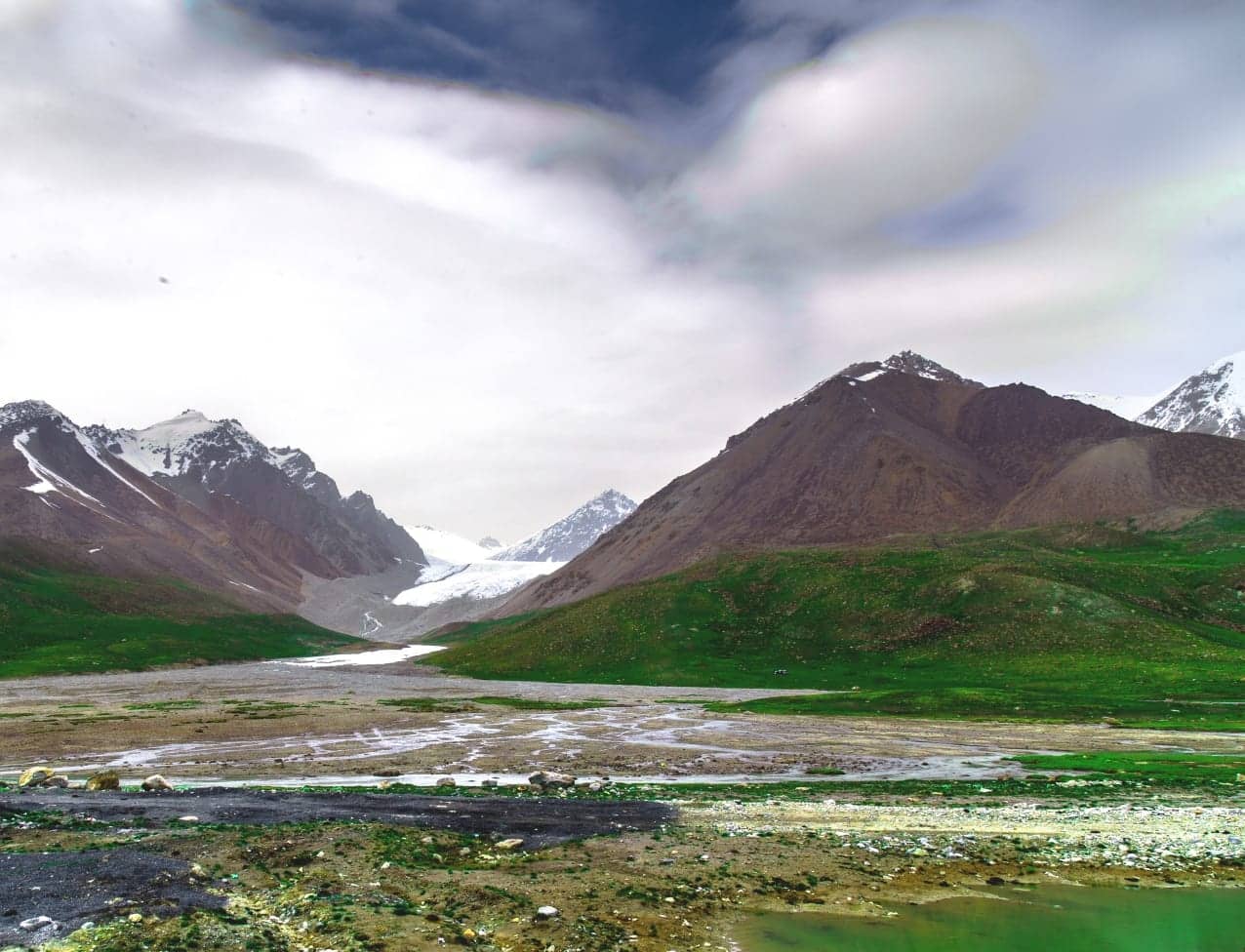A Karakoram glacier descending into a green valley near Passu